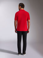 Alpinestars Endeavor Classic Polo, rood piqué poloshirt, achteraanzicht, gedragen met een zwarte broek, casual motorsport streetwear met geribde kraag en manchetten