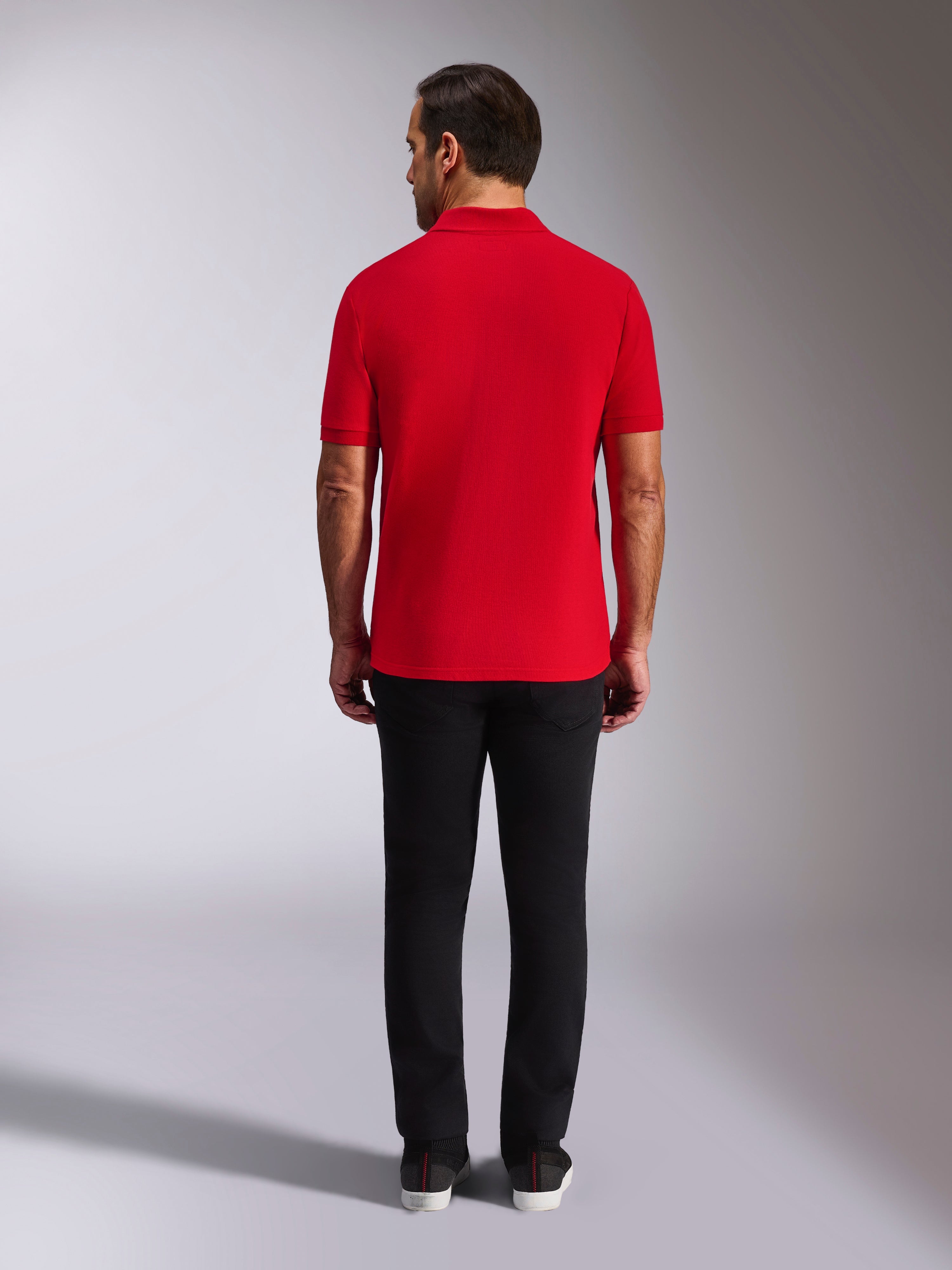 Alpinestars Endeavor Classic Polo, rood piqué poloshirt, achteraanzicht, gedragen met een zwarte broek, casual motorsport streetwear met geribde kraag en manchetten