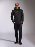 Alpinestars Insight Hoodie, zwarte pullover hoodie met wit Astars-logo op de borst en mouw, gedragen door een model met zwarte broek en zwarte sneakers, casual motorsport-geïnspireerde streetwear