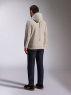 Alpinestars Insight Hoodie, achteraanzicht in cementgrijs, voorzien van een verticale zwarte streep met de tekst 'RACING AHEAD', casual streetwear-ontwerp, gedragen met een donkere jeans en zwarte schoenen.