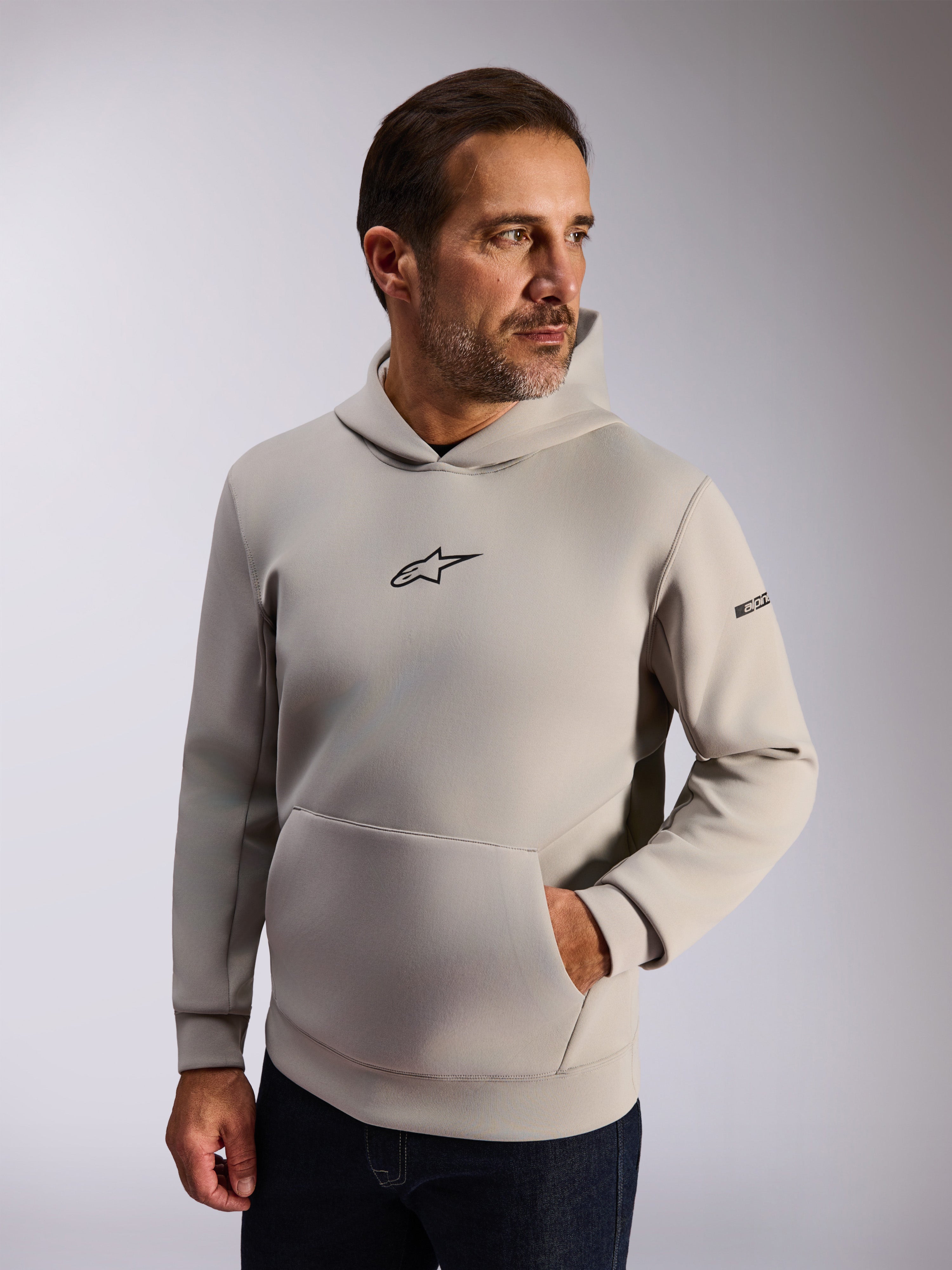 Alpinestars Insight Hoodie, casual lifestyle streetwear, cementgrijze fleece, zwart Astars-logo op de voorkant, kangoeroezak, woordmerk op de mouw, capuchon met meshvoering, moderne op motorsport geïnspireerde kleding