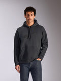 Alpinestars Emergent Oversized Hoodie, zwart, mannelijk model draagt een oversized pullover fleece hoodie, tonaal 3D-geborduurd Astars-logo, kangoeroezak, capuchon met trekkoord, casual op motorsport geïnspireerde streetwear