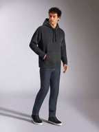 Alpinestars Emergent Oversized Hoodie, zwarte casual streetwear, ton-sur-ton 3D geborduurd Astars-logo op de borst, kangoeroezak, oversized pasvorm, gedragen door een mannelijk model met donkerblauwe denim jeans en zwarte sneakers