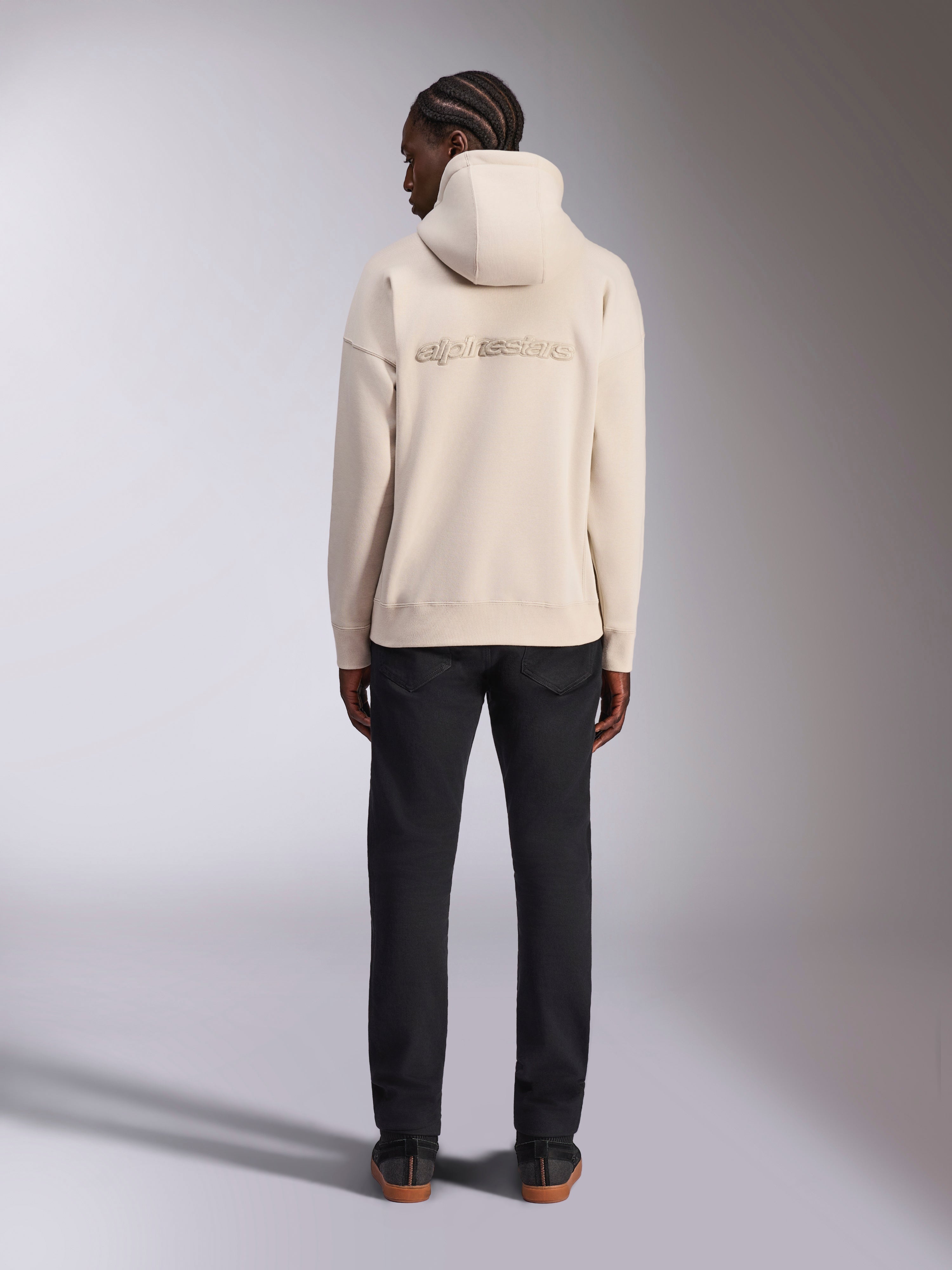 Alpinestars Emergent Oversized Hoodie, Off White, achteraanzicht met 3D-geborduurd Alpinestars-woordlogo, oversized fit fleece pullover, gecombineerd met een zwarte broek, casual streetwear-ontwerp