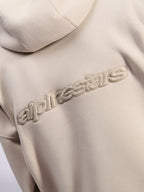 Alpinestars Emergent Oversized Hoodie, casual streetwear, zandkleur, detailweergave van tonaal 3D-geborduurd Alpinestars-woordlogo op de rug, premium fleece textuur