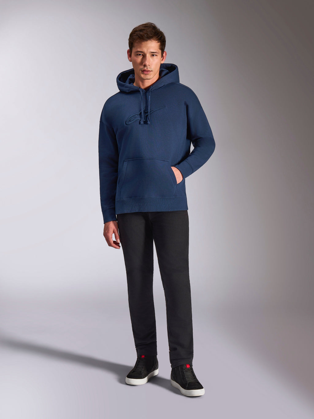 Alpinestars Emergent Oversized Hoodie, navy blauwe pullover fleece hoodie, tonaal 3D-geborduurd logo op de voorkant, gedragen door model met zwarte broek en sneakers, casual streetwear stijl.