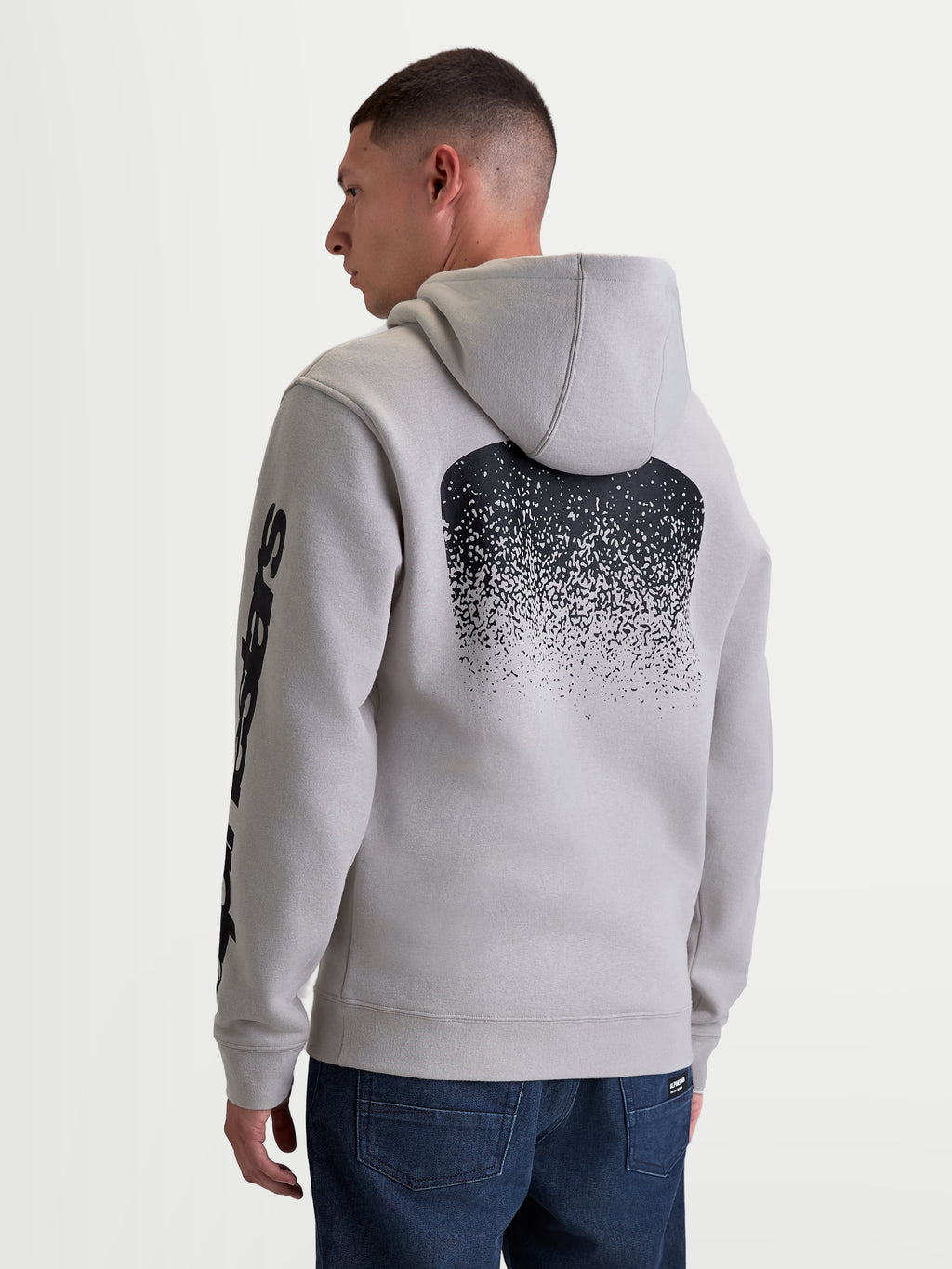 Alpinestars Obsessed hoodie, heren sportswear pullover fleece in cement grijs, voorzien van een grote zwarte MX-geïnspireerde gradiënt graphic op de rug en mouwlogo's, achteraanzicht op model, casual motorsport lifestyle kleding.