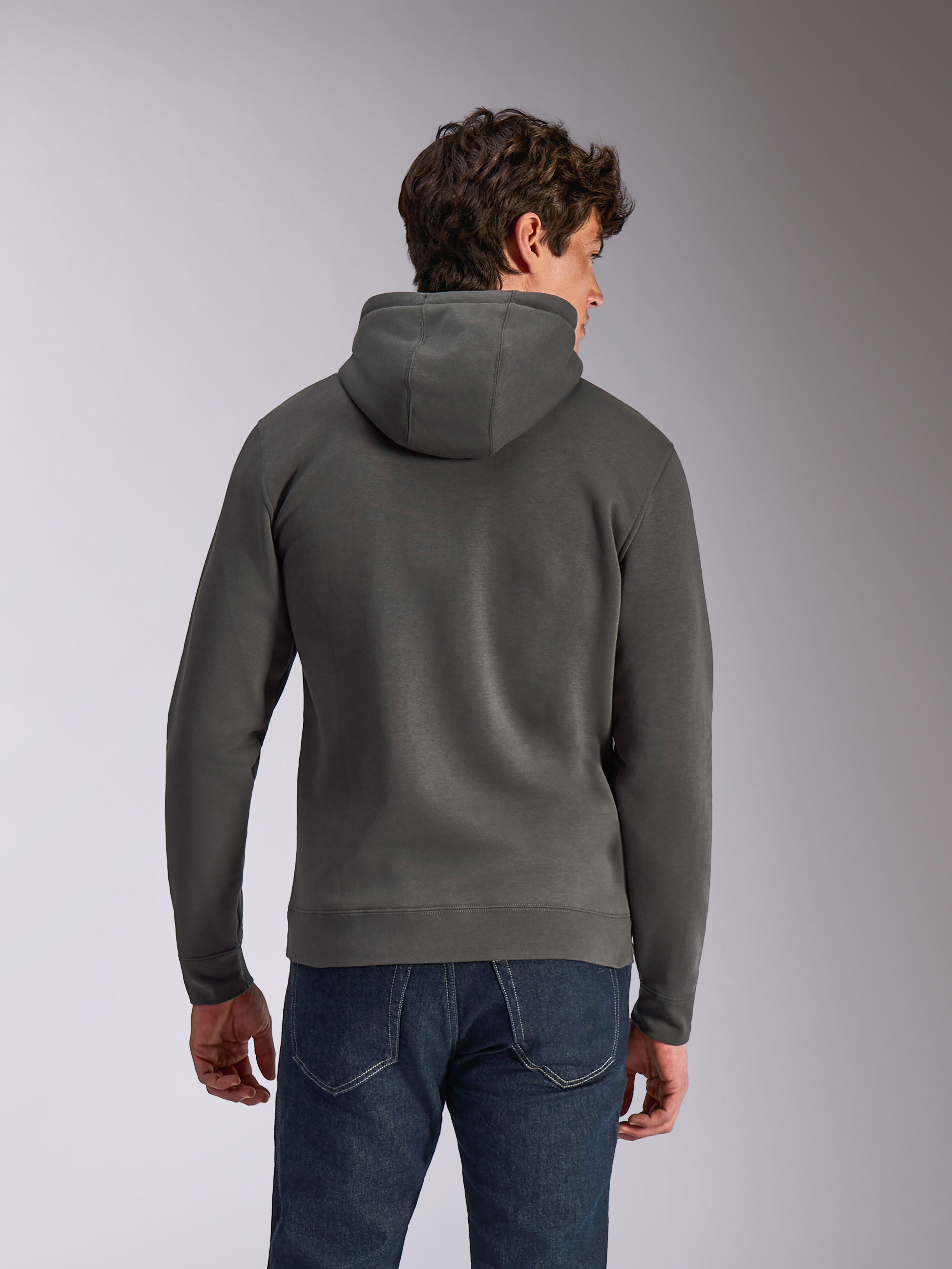 Alpinestars Ellipsoid Hoodie, Gunmetal grijs, casual sportkleding, achteraanzicht van een man die een fleece pullover met capuchon draagt, geribde zoom en manchetten, gecombineerd met een blauwe jeans