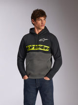 Alpinestars Parallel Hoodie, casual fleece pullover met kleurblokken, zwart en gunmetal met een felgele balk op de borst, Alpinestars woordlogo en wit sterlogo, gedragen door een mannelijk model met donkerblauwe jeans