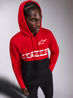 Alpinestars Parallel Hoodie, casual fleece pullover, rood en zwart color-blocked ontwerp, wit Alpinestars woordlogo en Astars-logo op de borst, gedragen door een man met de capuchon op en een zwarte broek, motorsport-geïnspireerde streetwear