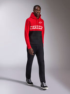Alpinestars Parallel Hoodie, casual sportkleding, rood en zwart kleurgeblokkeerd ontwerp, met een wit Alpinestars woordmerk en sterlogo op de borst, gedragen met zwarte broek en sneakers, moderne op motorsport geïnspireerde look
