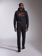 Alpinestars Pulse Hoodie, zwarte casual streetwear hoodie, rood en grijs Astars combo-logo met speed line fade op de borst, capuchon met trekkoord, kangoeroezak aan de voorkant, lange mouwen, gecombineerd met een zwarte broek en sneakers, op de motorsport geïnspireerd design
