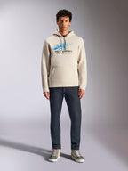 Alpinestars Pulse Hoodie, Off White, pullover met lange mouwen en capuchon met trekkoord, blauw en zwart Astars Combo Logo met speed line fade, gecombineerd met een donkere jeans en sneakers, casual motorsport streetwear