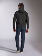 Alpinestars Cypher Hoodie, zwarte fleece met dubbele stof, achteraanzicht met een klein wit Alpinestars-logo op de linkerheup, hoge capuchon, gecombineerd met een donkerblauwe jeans, casual streetwear geïnspireerd op de motorsport