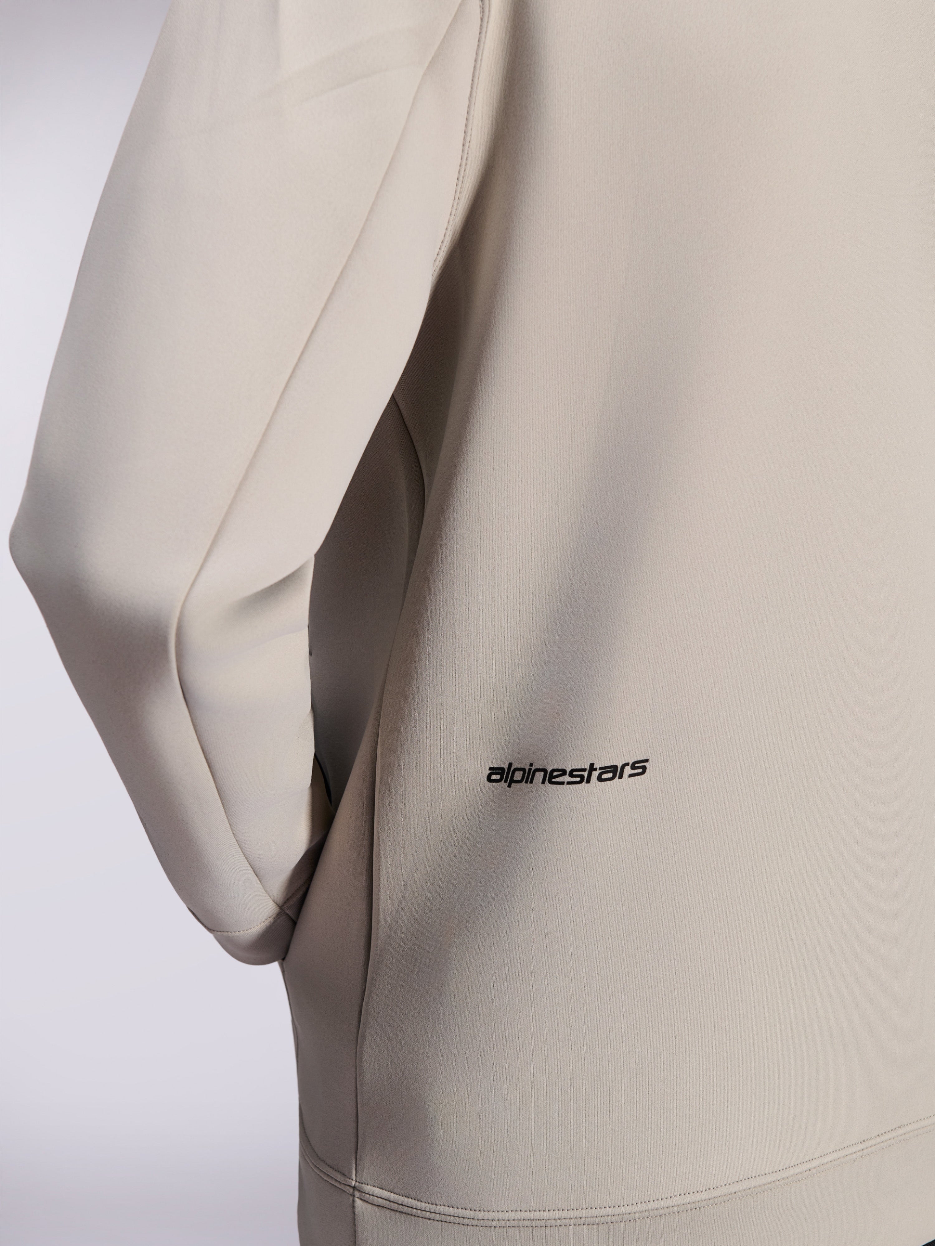 Alpinestars Cypher Hoodie, dubbelzijdige fleece hoodie met rits, Cementgrijs, close-up van klein zwart Alpinestars woordlogo op de onderrug, detail van zak in de zijnaad en gladde textuur van de stof