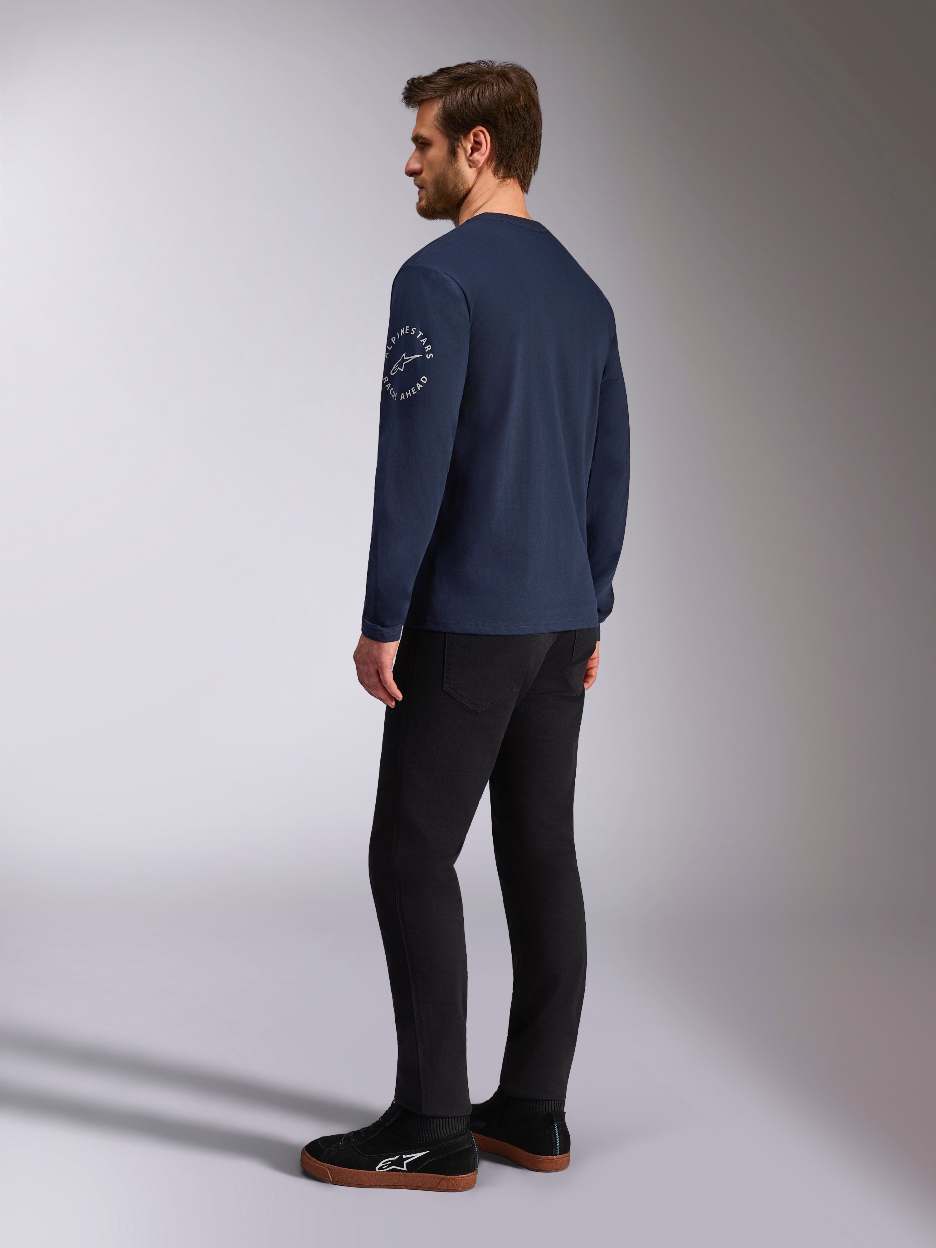 Alpinestars Mandatory CSF T-shirt met lange mouwen, navy, wit cirkelvormig logo op de mouw, achteraanzicht, gedragen met zwarte broek en zwarte sneakers, casual motorsport streetwear