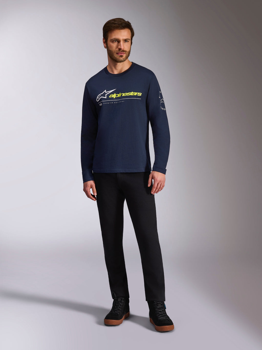 Alpinestars Mandatory CSF Tee, T-shirt met lange mouwen, donkerblauw, wit Astars-logo met neongeel woordlogo, gedragen door een model met een zwarte broek en zwarte sneakers, casual motorsport streetwear