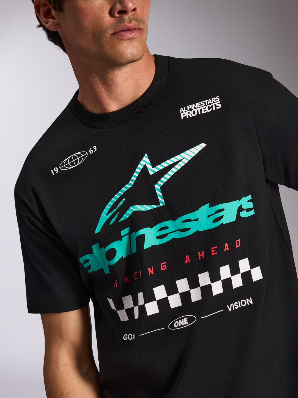 Alpinestars Aplomb Oversized CSF Tee, T-shirt met korte mouwen, zwart, blauwgroen en wit gestreept Astars-logo, rode 'Racing Ahead'-tekst met geblokt vlagpatroon, casual motorsport streetwear