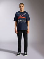 Alpinestars Aplomb Oversized CSF Tee, marineblauw T-shirt met korte mouwen, grote grafische print op de borst met oranje en rood kleurverloop logo en geblokt patroon, gedragen door model met zwarte broek en sneakers, casual motorsport streetwear