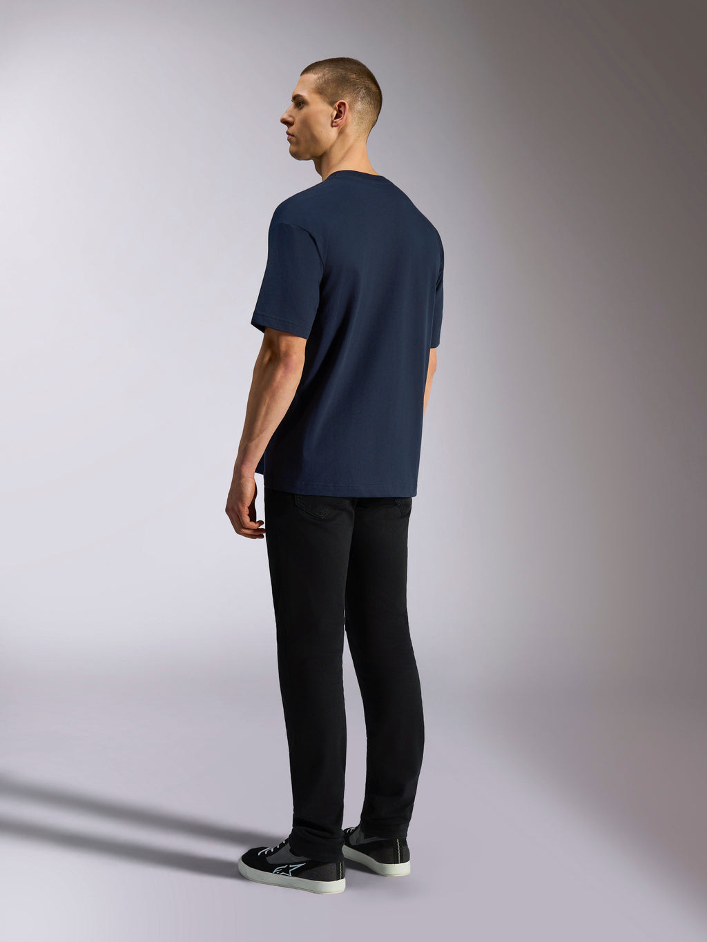 Alpinestars Aplomb Oversized CSF Tee, T-shirt met korte mouwen, navy, achteraanzicht op model, gedragen met zwarte broek en sneakers, casual op de motorsport geïnspireerde streetwear