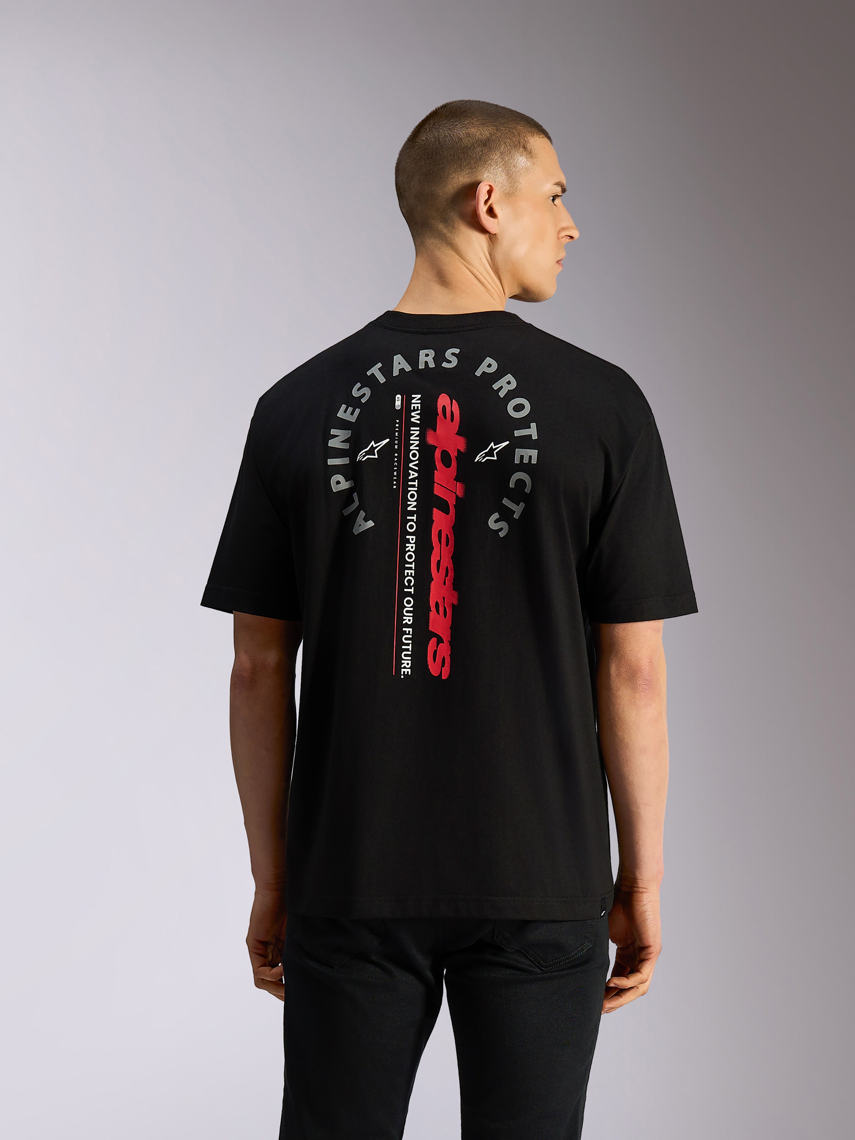 T-shirt Alpinestars Overhang Oversized CSF, t-shirt à manches courtes, noir, vue de dos montrant le mot-symbole Alpinestars vertical rouge et le graphique circulaire gris « Alpinestars Protects », streetwear décontracté inspiré du sport automobile