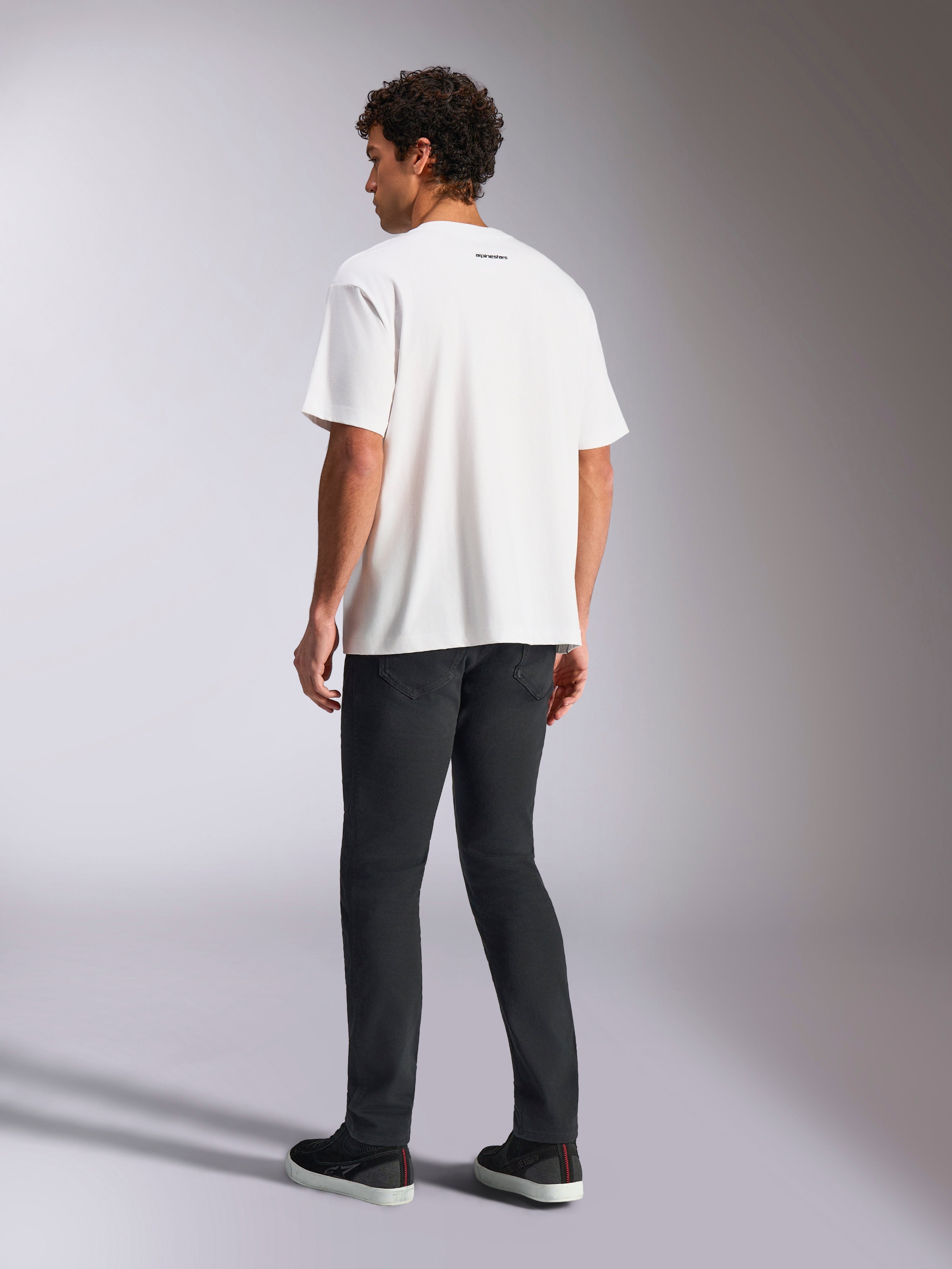 Alpinestars Focused Oversized CSF Tee, T-shirt met korte mouwen, wit, klein zwart Alpinestars-tekstlogo op de achterkant van de nek, gedragen met een zwarte broek, oversized pasvorm, casual motorsport-geïnspireerde streetwear