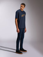 Alpinestars Alter Oversized CSF Tee, T-shirt met korte mouwen, marineblauw, geel en oranje Astars-logo, gedragen door een model met donkere jeans en zwarte sneakers, casual op motorsport geïnspireerde streetwear