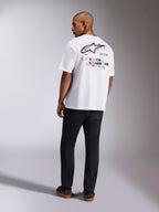 Alpinestars Wild Oversized CSF Tee, T-shirt met korte mouwen, wit, achteraanzicht van model in oversized shirt met levendig meerkleurig Astars-logo en gestapelde tekst op de rug, casual op motorsport geïnspireerde streetwear