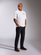 Alpinestars Wild Oversized CSF Tee, T-shirt met korte mouwen, wit, met een klein meerkleurig Astars-logo op de borst, gedragen door een model met een zwarte broek en zwarte sneakers, casual motorsport-geïnspireerde streetwear