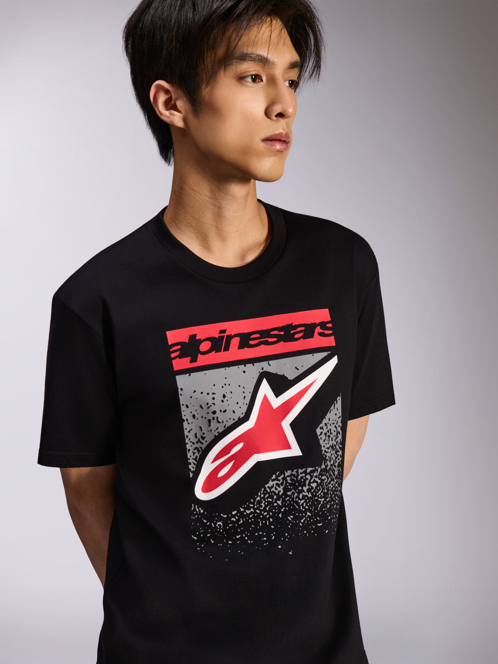 Alpinestars Noka CSF Tee, T-shirt met korte mouwen, zwart, voorzien van een rood logoblok en groot rood-wit Astars-logo met een grijze getextureerde achtergrond, casual motorsport streetwear
