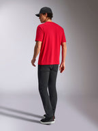 Alpinestars Noka CSF Tee, T-shirt met korte mouwen, rood, achteraanzicht, gecombineerd met een zwarte broek en een zwarte baseballpet, casual streetwear geïnspireerd op de motorsport