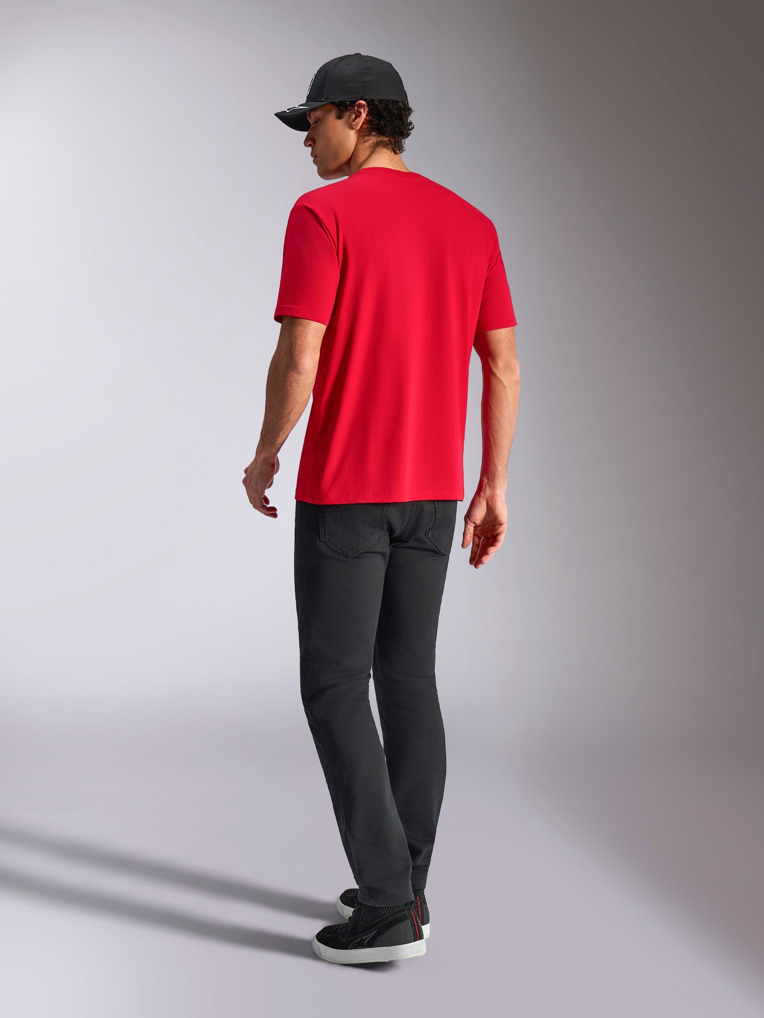 Alpinestars Noka CSF Tee, T-shirt met korte mouwen, rood, achteraanzicht, gecombineerd met een zwarte broek en een zwarte baseballpet, casual streetwear geïnspireerd op de motorsport