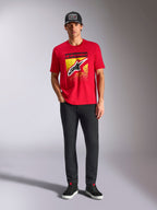 Alpinestars Noka CSF Tee, rood T-shirt met korte mouwen, voorzien van een groot Astars-logo op de voorkant met een geel-zwarte MX-kleurovergang, gedragen met een zwarte broek en zwarte pet, casual motorsport streetwear