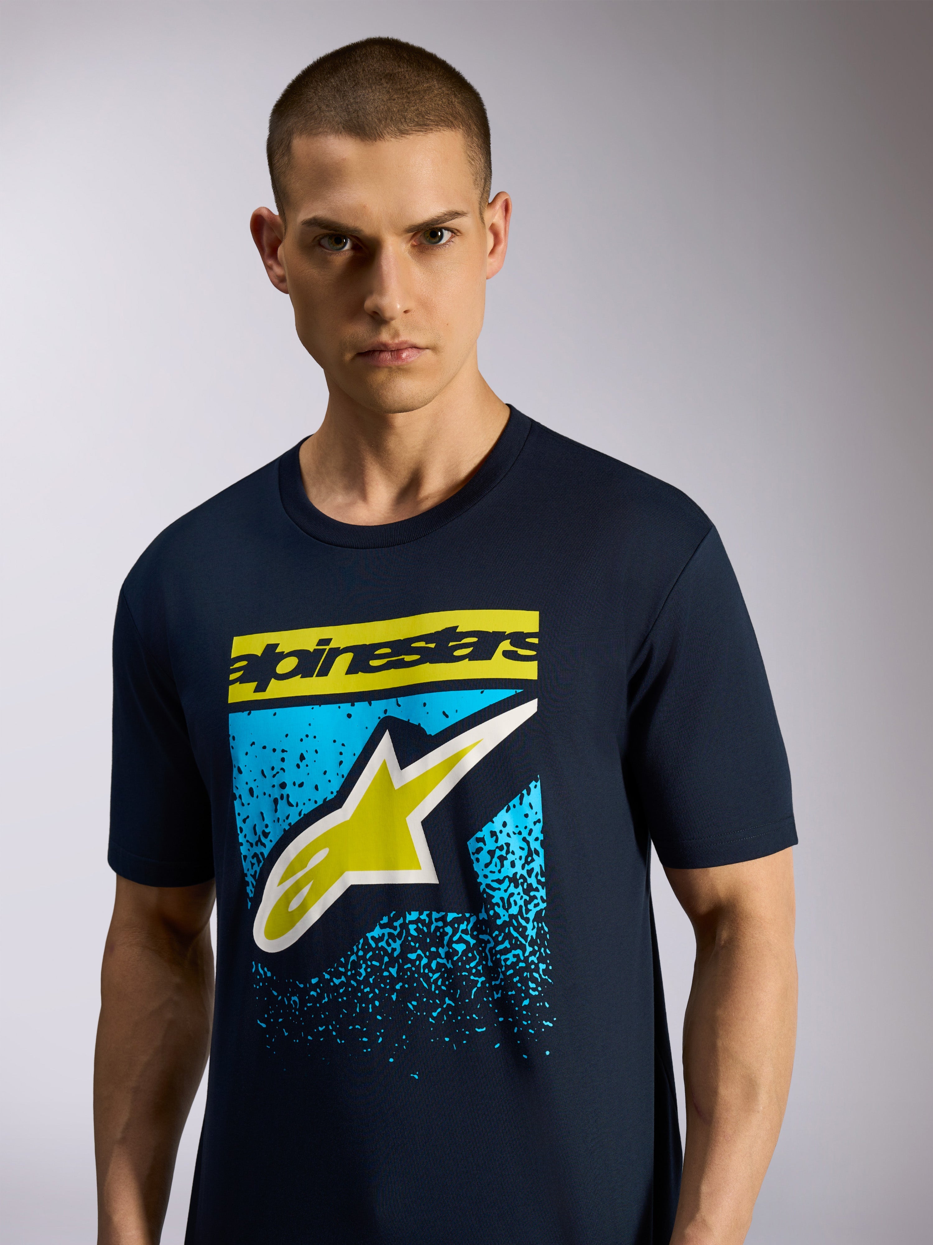 Alpinestars Noka CSF Tee, T-shirt met korte mouwen, marineblauw, voorzien van Astars-logo op de voorkant met geel woordmerk en blauwe gespikkelde graphic, casual motorsport sportswear