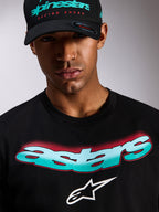 Alpinestars Ellipsoid CSF Tee, T-shirt met korte mouwen, zwart, Astars-woordmerk met kleurverloop in groenblauw en wit met rode halftoon-details, wit Astars-logo, gedragen met bijpassende zwarte Alpinestars pet, casual motorsport streetwear