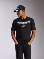 Alpinestars Ellipsoid CSF Tee, T-shirt met korte mouwen, zwart, Astars-woordmerk met teal en roze kleurverloop en wit logo, gedragen door een model met bijpassende Alpinestars-pet en zwarte jeans, casual motorsport streetwear