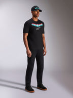 Alpinestars Ellipsoid CSF Tee, zwart T-shirt met korte mouwen, Astars-graphic met groenblauw en rood kleurverloop en wit logo, mannelijk model in casual streetwear met zwarte pet en broek