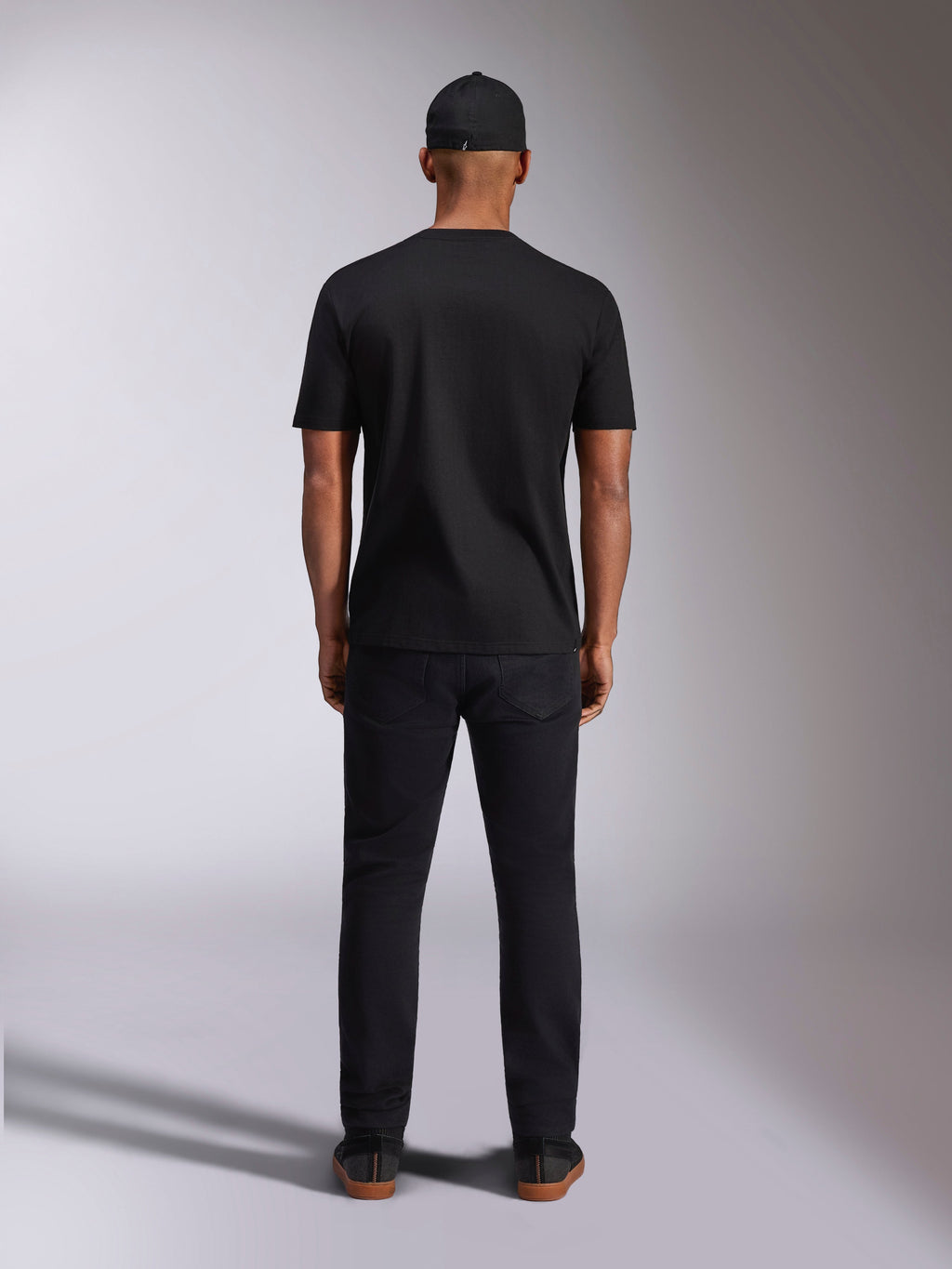 Alpinestars Plate CSF Tee, T-shirt met korte mouwen, zwart, achteraanzicht op model, gedragen met zwarte pet en broek, casual motorsport streetwear