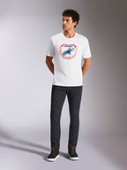 Alpinestars Plate CSF Tee, T-shirt met korte mouwen, wit, met een Astars MX plaatgrafiek aan de voorzijde met oranje en blauwe accenten, gedragen door een model met een zwarte broek en sneakers, casual motorsport streetwear