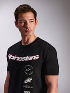 Alpinestars Abus CSF Tee, T-shirt met korte mouwen, zwart, gedragen door een model, voorzien van een wit Alpinestars script-logo met rode omtrek en gestapelde grafische logo's op de borst, casual motorsport streetwear