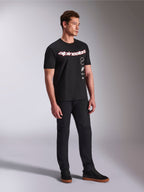 Alpinestars Abus CSF Tee, T-shirt met korte mouwen, zwart, met gebogen rood en wit Alpinestars-logo en verticaal gestapelde graphics, gedragen met zwarte broek en sneakers, casual streetwear geïnspireerd op motorsport