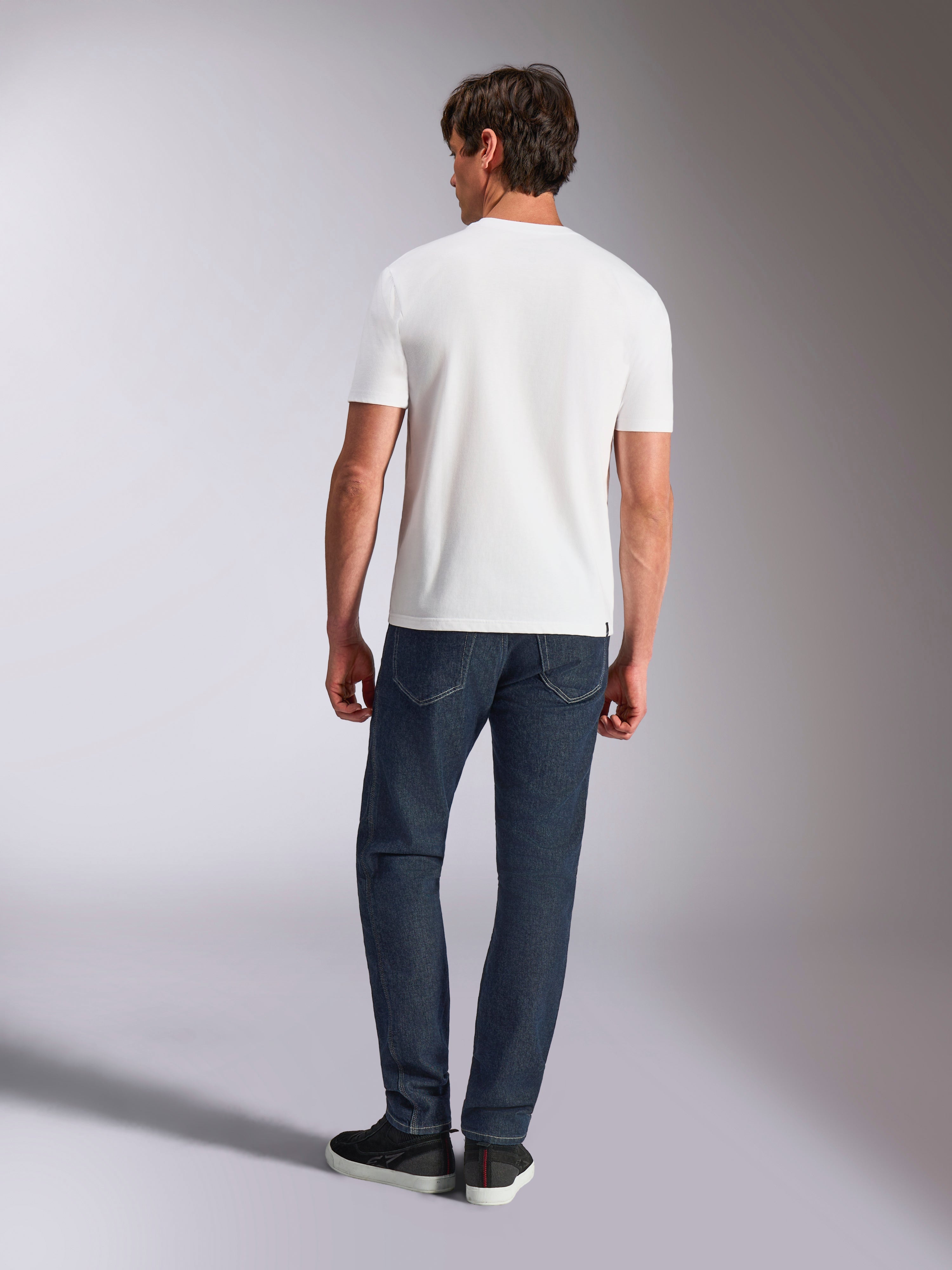 Alpinestars Abus CSF Tee, T-shirt met korte mouwen, wit, achteraanzicht van model in wit T-shirt met donkere denim jeans, casual motorsport-geïnspireerde streetwear