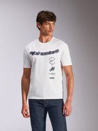 Alpinestars Abus CSF Tee, T-shirt met korte mouwen, wit, gebogen Alpinestars-logo met meervoudige gestapelde graphics op de borst, gedragen door model met donkere denim jeans, casual motorsport streetwear