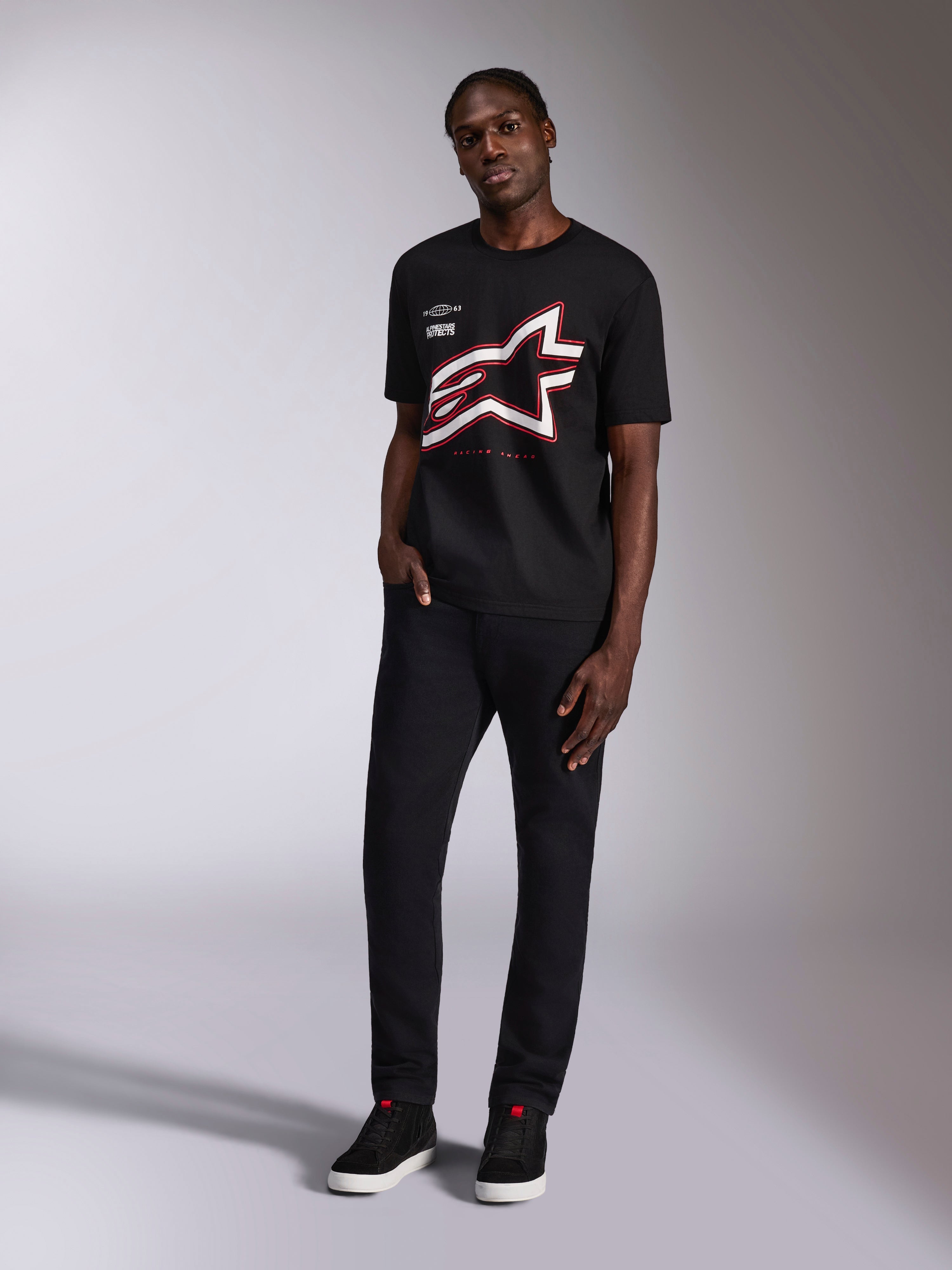Alpinestars Authority CSF Tee, zwart T-shirt met korte mouwen, groot bijgesneden Astars-logo met rode en witte omtrek, gedragen door een model, casual motorsport streetwear
