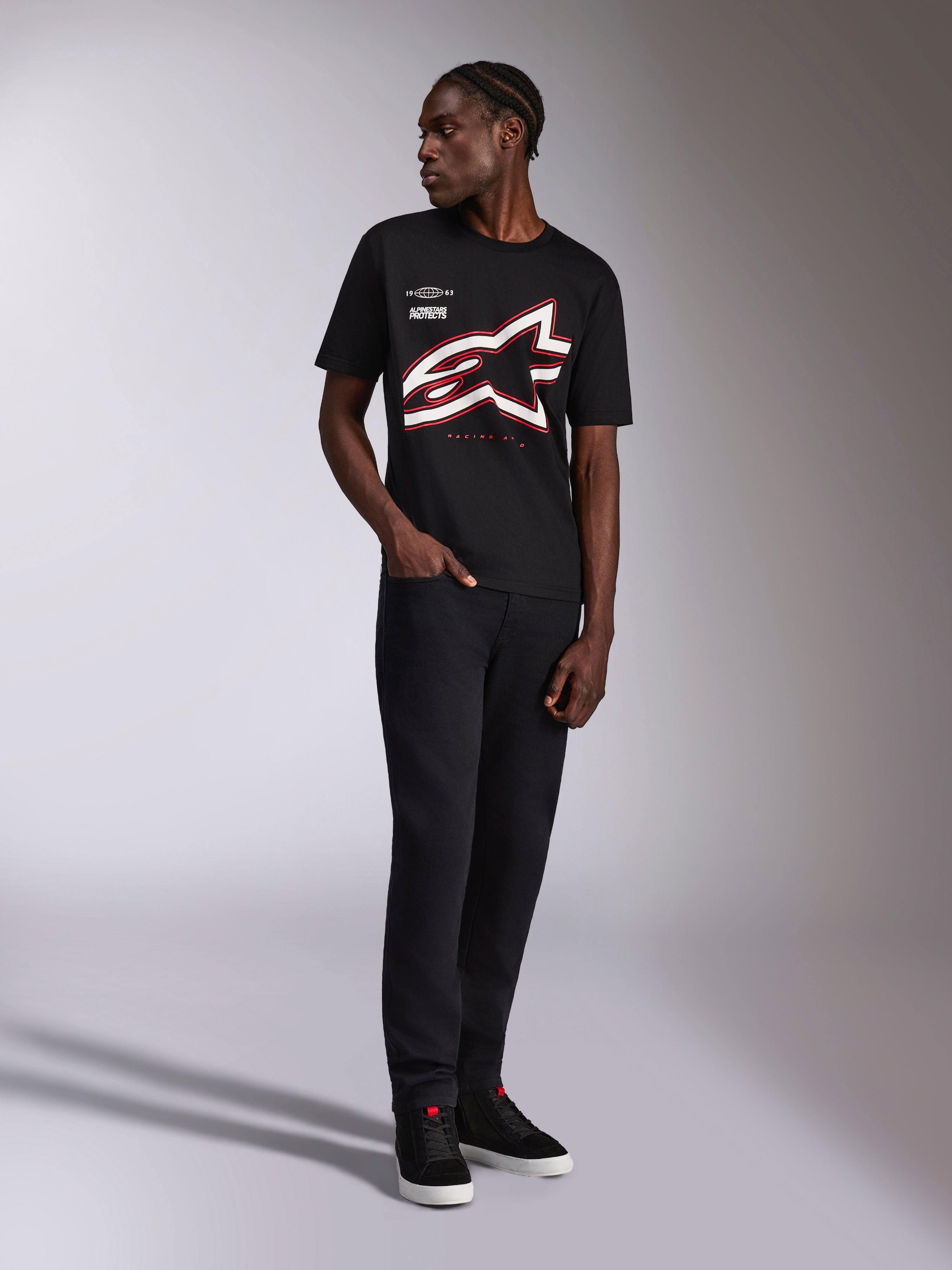 Alpinestars Authority CSF Tee, T-shirt met korte mouwen, zwart, groot rood en wit bijgesneden Astars omtreklogo, gedragen door een model met zwarte broek en sneakers, casual motorsport streetwear