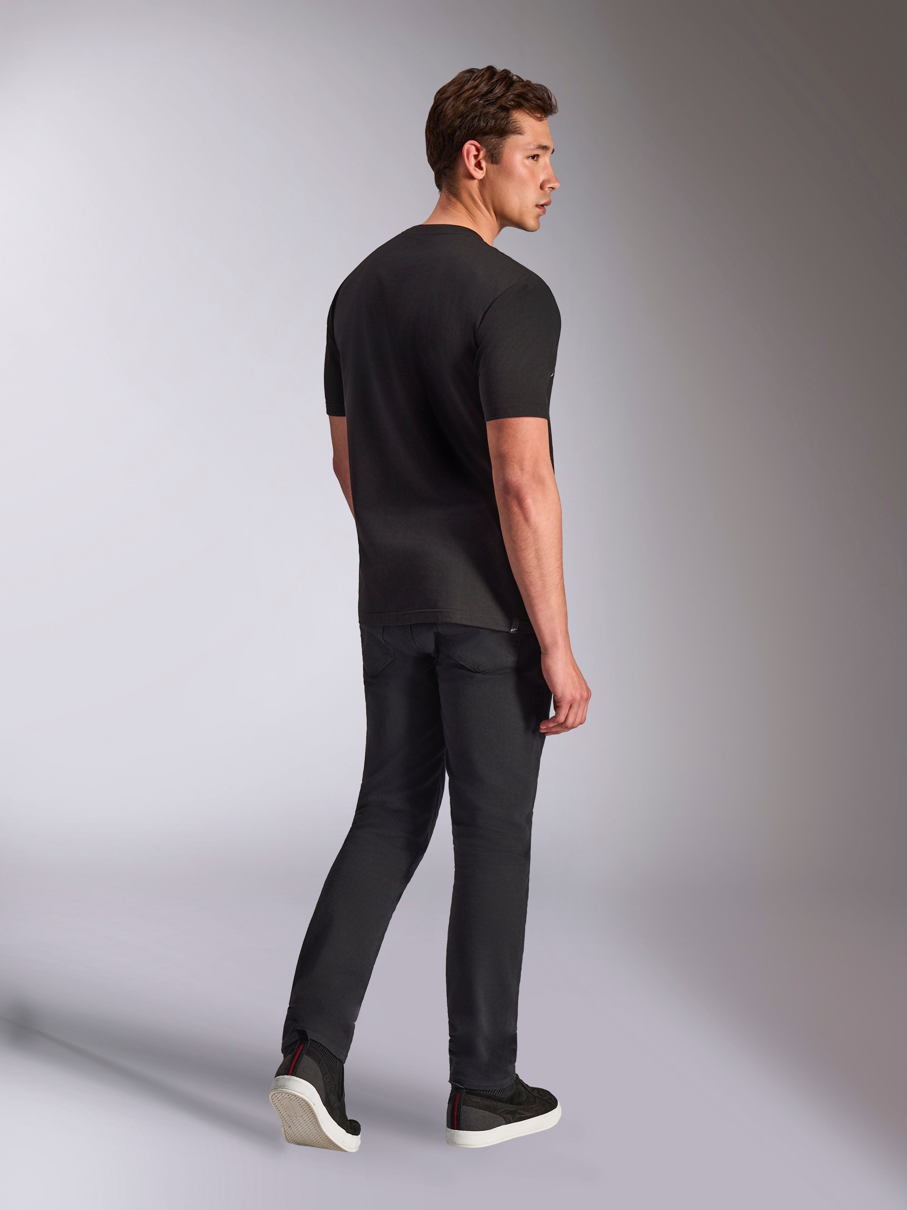 Alpinestars Trifecta CSF Tee, T-shirt met korte mouwen, zwart, achteraanzicht van een man die het shirt draagt met een zwarte jeans en sneakers, casual motorsport streetwear