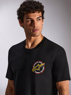 Alpinestars Aorbit CSF Tee, t-shirt met korte mouwen, zwart, ronde grafische opdruk op de borst met "Always Fast Made to Last" en geel Astars-logo, gedragen door model, casual motorsport streetwear