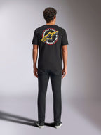 Alpinestars Aorbit CSF Tee, T-shirt met korte mouwen, zwart, van achteren gezien op een model met een zwarte broek, voorzien van een grote 'Always Fast Made to Last' opdruk met geel Astars-logo, casual motorsport streetwear