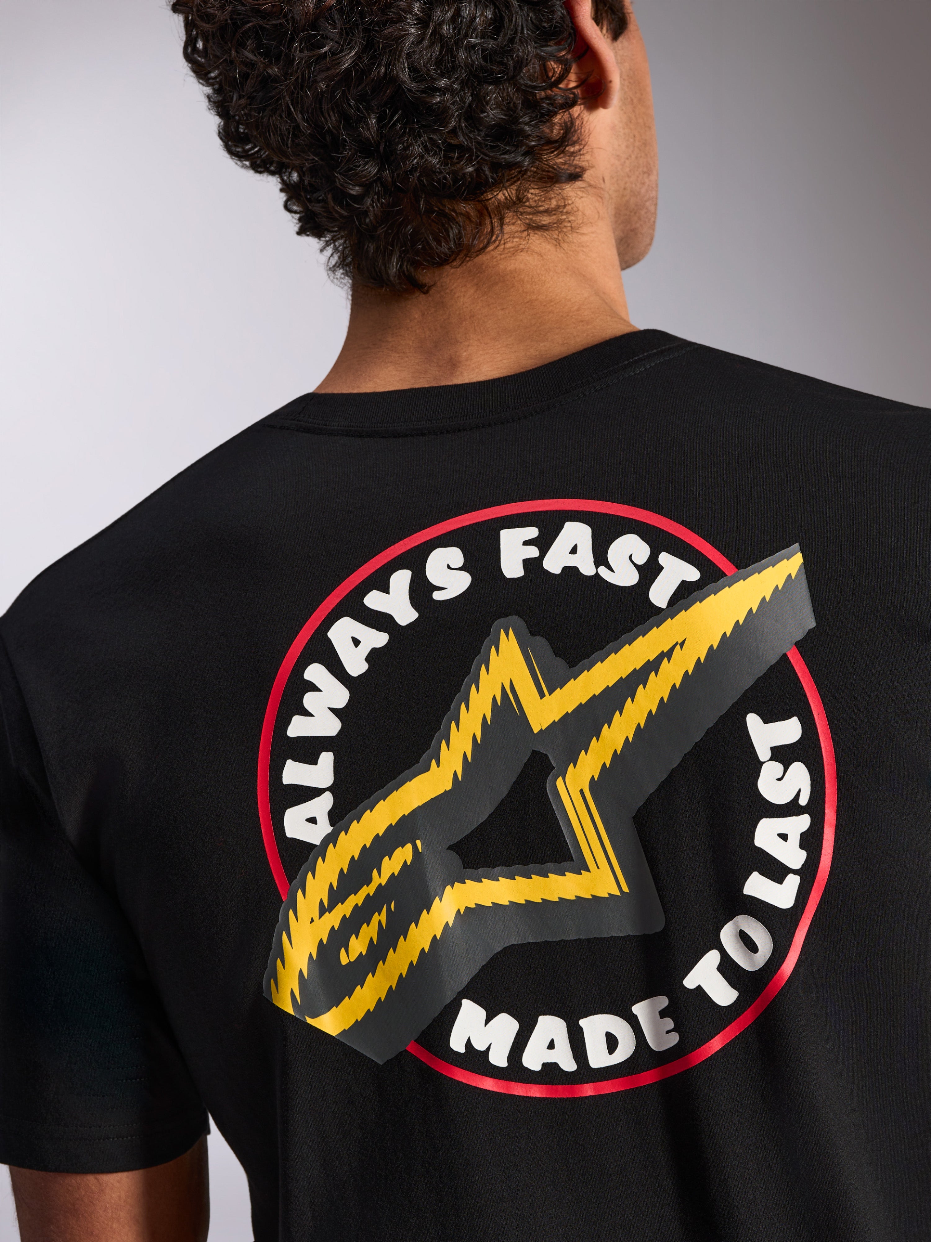 Alpinestars Aorbit CSF Tee, T-shirt met korte mouwen, zwart, detail van de achterkant met Always Fast Made to Last-graphic en geel sterlogo, casual streetwear geïnspireerd op de motorsport