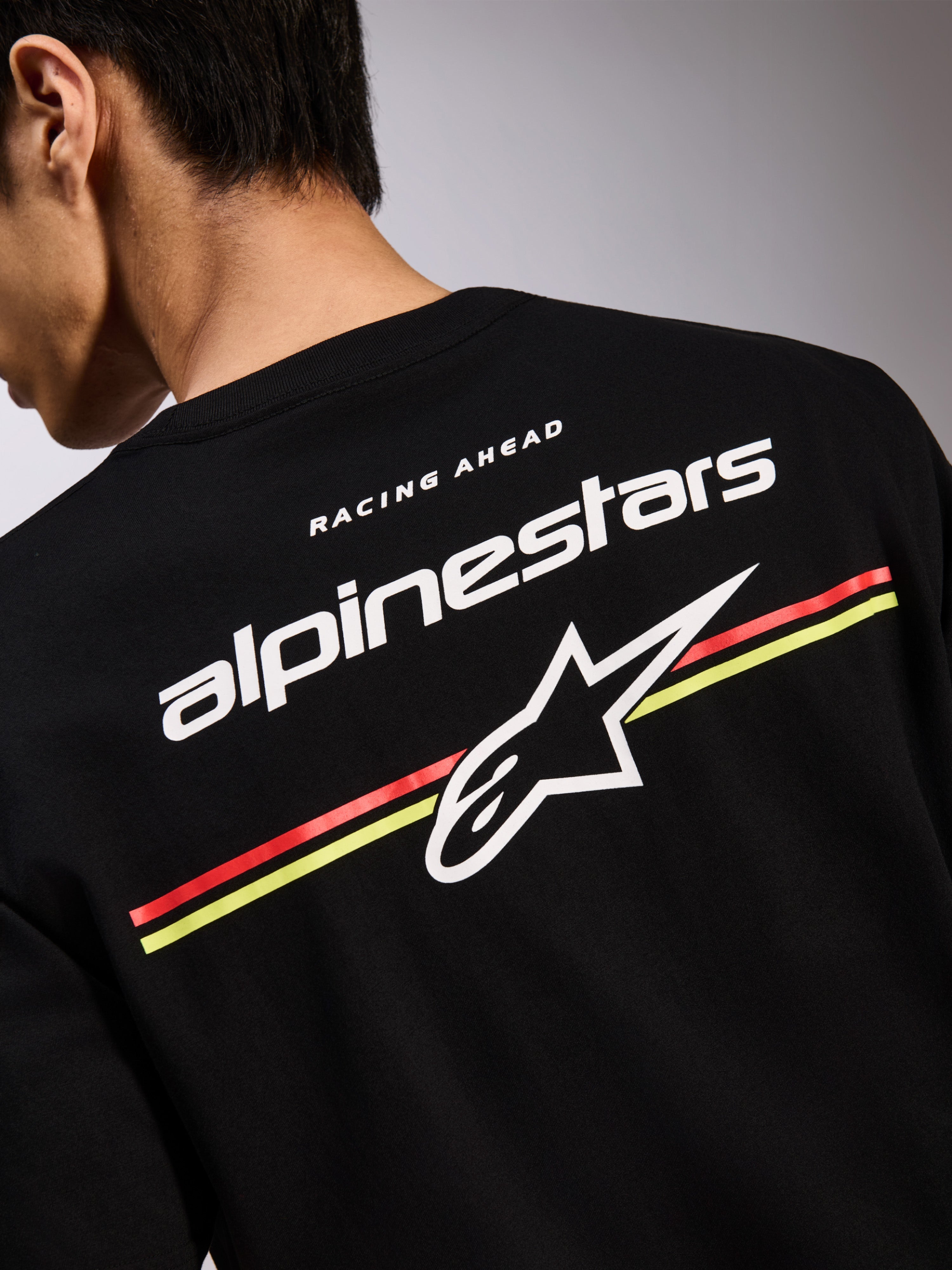 Alpinestars Lanes CSF Tee, zwart T-shirt met korte mouwen, grafische print op de achterkant met witte Alpinestars en Astars logo's over rode en gele strepen, casual motorsport streetwear